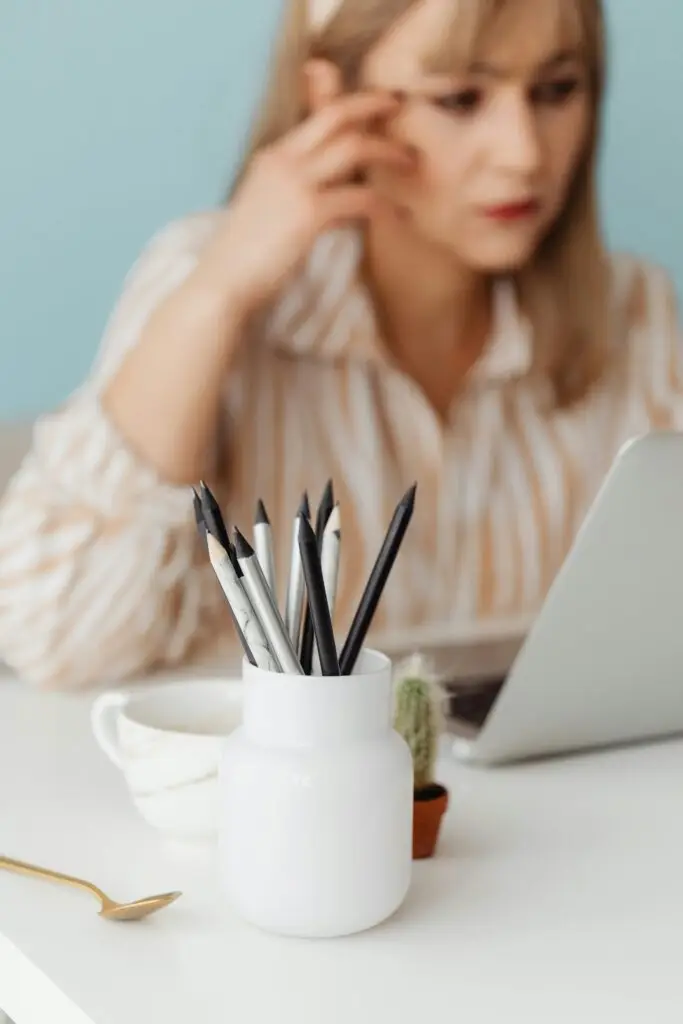 Minimalist workspace featuring pencils and a blurred woman using a laptop.